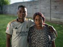 A man with his arm around a woman, both looking into the camera and smiling