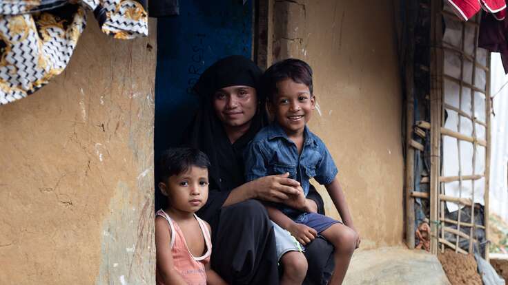 A mother sitting with her two sons on a stoop